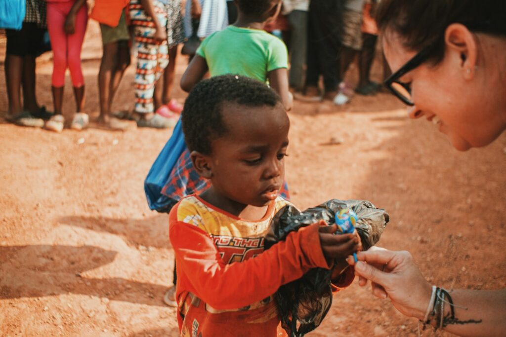 photo by michael ali a woman is handing something to a child